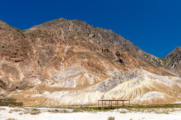 A volcanic mountain with sulphur deposits on the slopes on background of a clear blue sky - 231741932