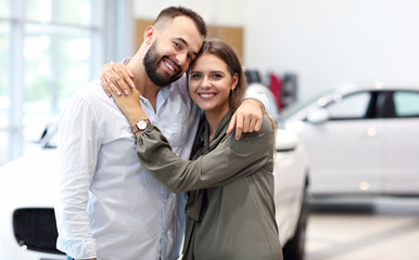Adult couple choosing new car in showroom