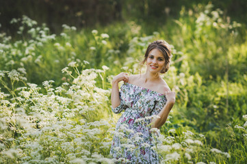 Fototapeta na wymiar Portrait of a happy pregnant woman in a clearing of white flowers of a for
