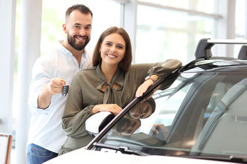 Fototapeta na wymiar Adult couple choosing new car in showroom