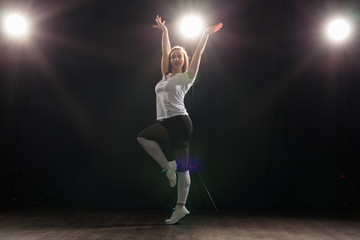 People and dance concept - Young woman dancing jazz funk over dark background