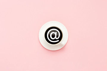 White cup on a saucer, black coffee, pink background. Email sign. Flat lay, top view