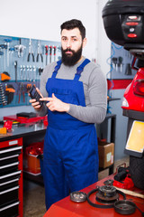 Worker considers the cost of repairing the motorcycle