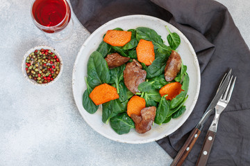 Warm spinach salad with chicken liver and baked pumpkin. Delicious dinner with red wine for gourmets