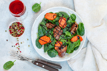 Warm spinach salad with chicken liver and baked pumpkin with spices and balsamic. Delicious dinner with red wine for gourmets.