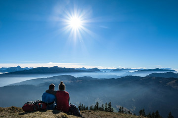 a couple resting on top of the riedberghorn after a hiking tour in the allgaeuer alps, germany,...
