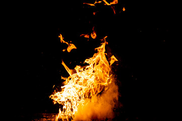 Burning woods with firesparks, flame and smoke. Strange weird odd elemental fiery figures on black background. Coal and ash. Abstract shapes at night. Bonfire outdoor on nature. Strenght of element.