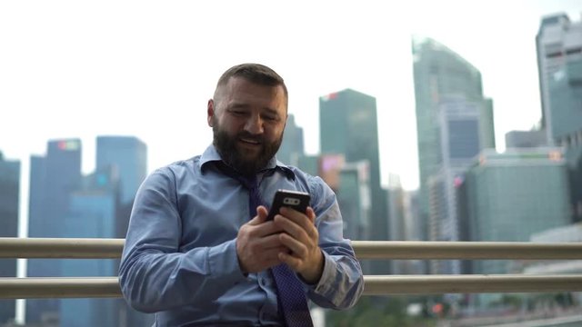 Happy businessman taking photo with cellphone in the city