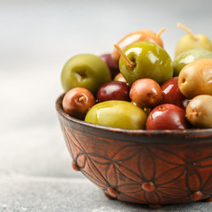 Mixed marinated olives (green and purple) in ceramic bowl. Selective focus