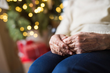 A close-up of a senior woman sitting at home at Christmas time.