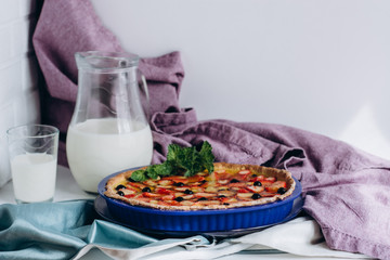 Homemade pies with jam and glass of milk on white table and violet cloth background