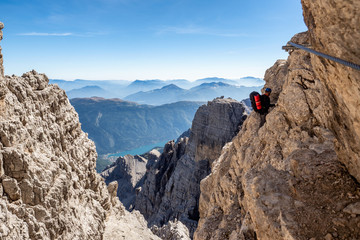Male mountain climber on a Via Ferrata in breathtaking landscape of Dolomites Mountains in Italy....