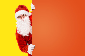 Santa Claus is looking out of colorful advertisement board and copy space