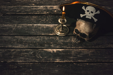 Pirate captain table with pirate hat, human skull and burning candle. Treasure hunter concept background.