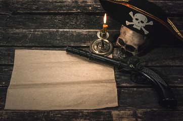 Pirate treasure map with copy space, pirate captain hat, human skull, musket and burning candle. Treasure hunter concept background.