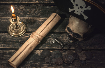 Pirate treasure map scroll, pirate captain hat, human skull, ancient coins and burning candle....