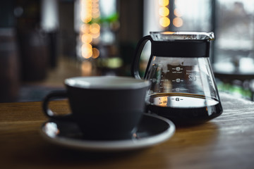 cup of coffee and teapot on table in cafe
