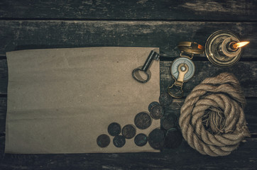 Pirate treasure map with copy space, compass, key from treasure map, mooring rope, and burning candle on wooden table background. Treasure hunter concept background.