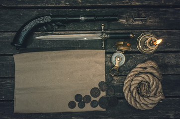 Pirate treasure map with copy space, compass, key from treasure map, mooring rope, musket, dagger and burning candle. Treasure hunter concept background.