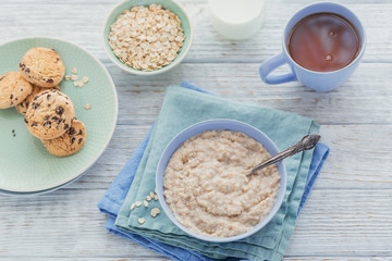 Oatmeal porridge bowl on the white wooden background.