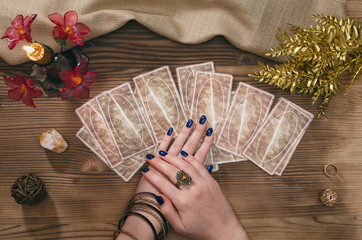 Tarot cards and hands of fortune teller on wooden table background.