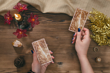 Tarot cards and hands of fortune teller on wooden table background.