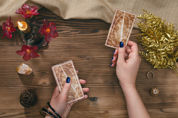 Tarot cards and hands of fortune teller on wooden table background.