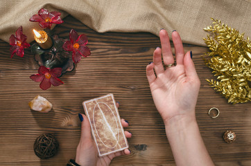 Tarot cards and hands of fortune teller on wooden table background.