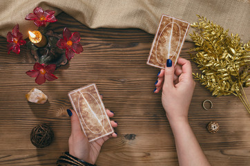 Tarot cards and hands of fortune teller on wooden table background.