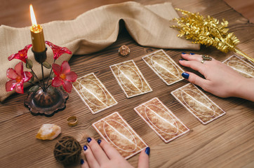 Tarot cards and hands of fortune teller on wooden table background.