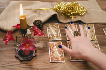 Tarot cards and hands of fortune teller on wooden table background.
