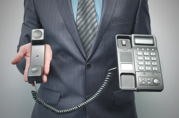 Telephone and phone handset in the businessman hands isolated on the white background.