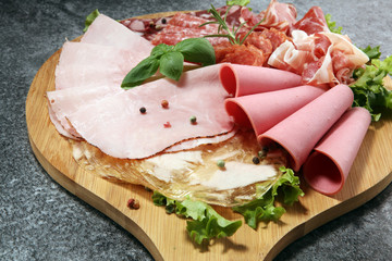 Food tray with delicious salami, pieces of sliced ham, sausage and salad. Meat platter with selection.