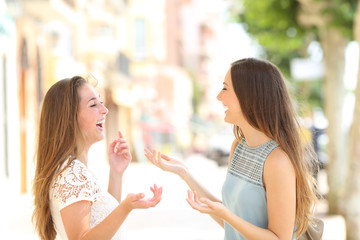 Two happy friends talking and lauging in the street