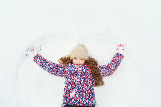 Little girl on a snow showing angel figures.
