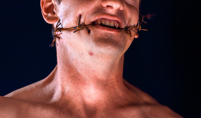 barbed wire, in the mouth, portrait on black background, blood on face