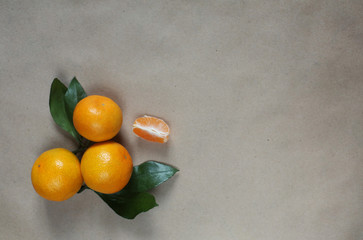 Craft paper background with delicious tangerines and leaves on the sides, with copy space for the text
