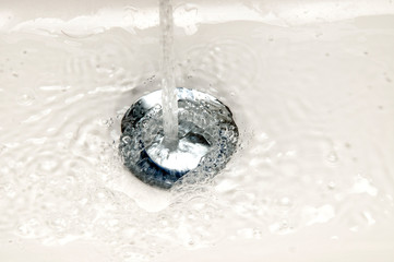 Wasser l&auml;uft in einen Abfluss in einem Waschbecken