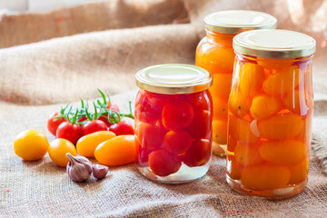 Glass jars with homemade pickled tomatoes, sealed with metal lid