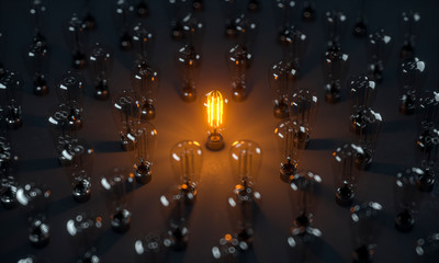 Eine leuchtende Edison Glühlampe umringt von vielen nicht leuchtenden Glühlampen - obrazy, fototapety, plakaty