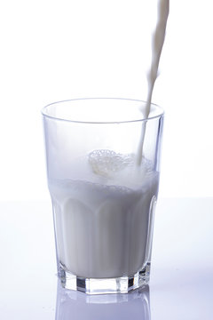 pouring a glass of milk creating splash on a white background