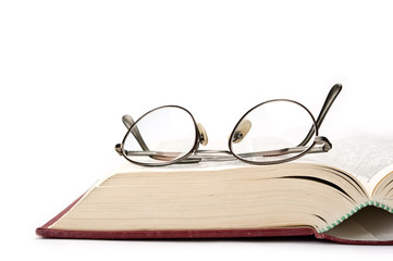 Book and eyeglasses on white background.