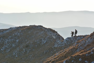 Beautiful view on mountains with silhouette of couple and with dog.