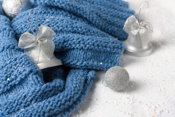 Fototapeta na wymiar wool knitted scarf handmade deep blue colow with silver christmas toys on the snow table white