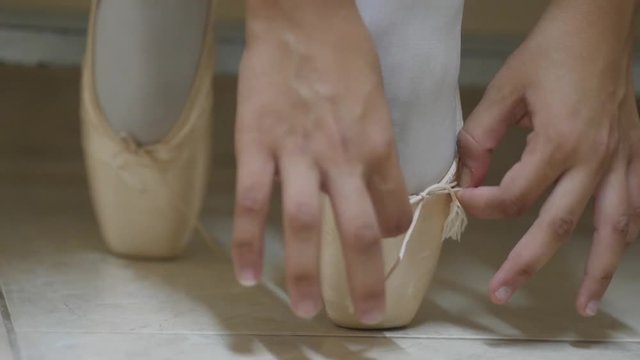 Close-up of ballet dancer's feet as she ties the laces of her ballet slipper
