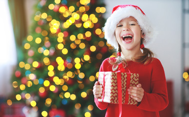 happy child girl with christmas gifts near tree in  morning