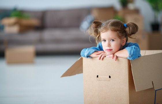 child girl sitting in box for moving to new apartment.