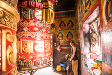 A woman stands next to a large prayer wheel of the temple of Boudhanath Stupa, Kathmandu, Nepal, Asia
