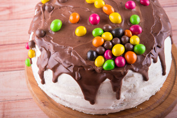 Tasty mousse cake with chocolate icing drips and colored glazed peanut balls