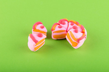 Toy pink cake made of modelling clay on green background